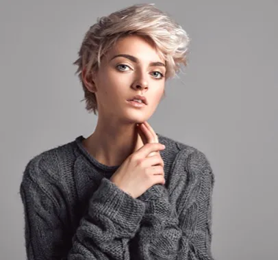 Jeune femme aux cheveux courts blonds, portant un pull gris tricoté, la main sur le cou à Valence dans le Tarn-et-Garonne 82