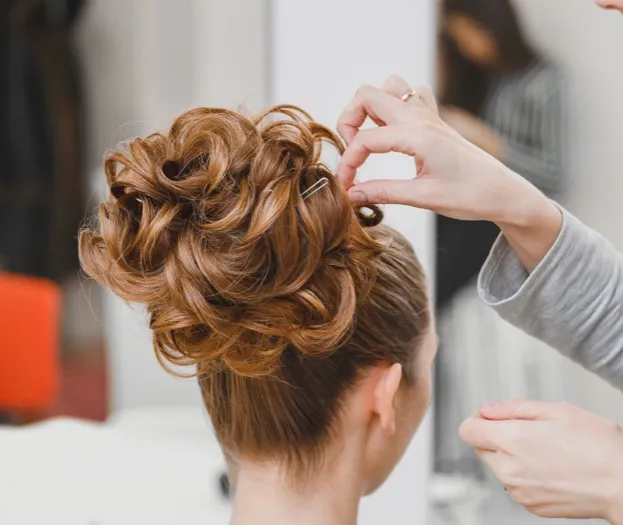 Coiffeur créant un chignon bouclé sur une femme, vue arrière à Valence dans le Tarn-et-Garonne 82